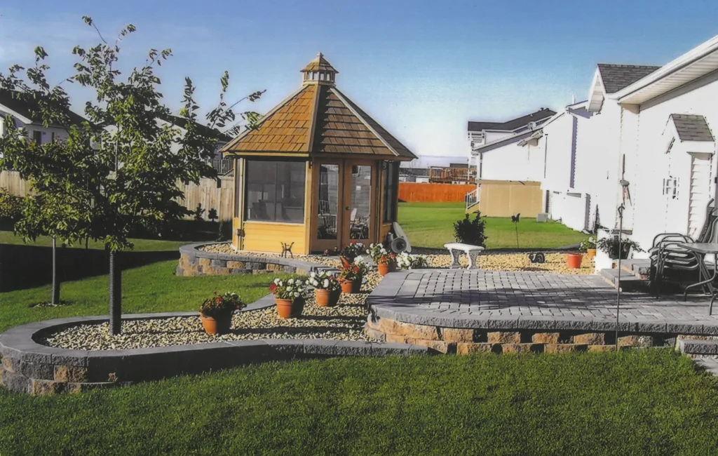 SKM_C451i24121707490 Backyard stone patio with section for trees and plants and a gazebo.