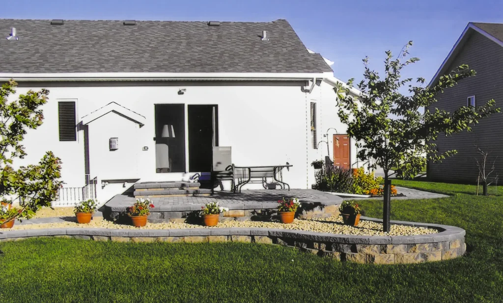 SKM_C451i24121707501 Stone outdoor backyard patio with stairs, ledges, section for trees and plants.