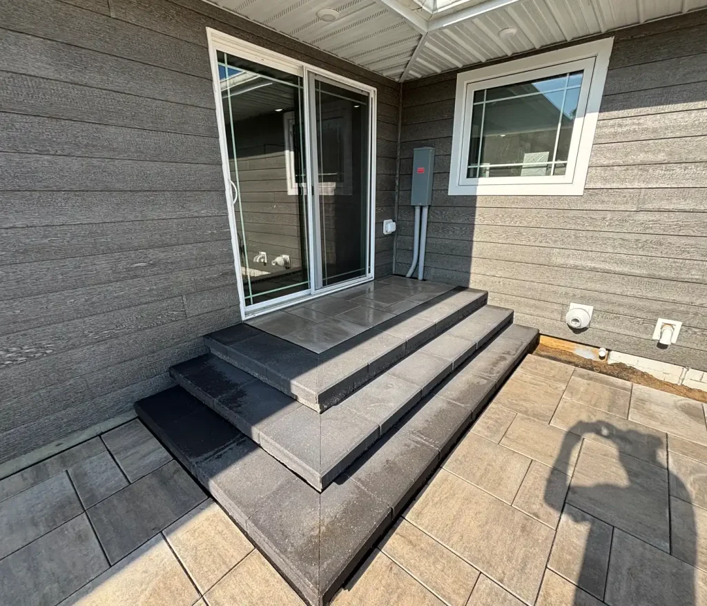 Patio1-4 Outdoor patio with tiled steps, sliding door, and gray siding.