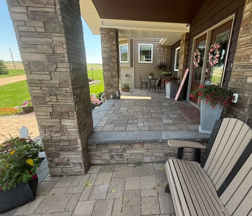 Patio2-3 Front porch with stone pillars, flower planters, patio furniture, and landscape view.