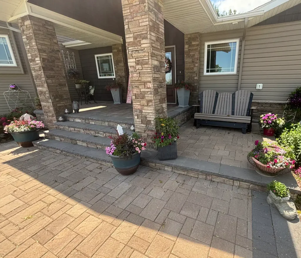 Patio2-4 House entrance with porch, stone columns, and potted flowers with a new brick patio.